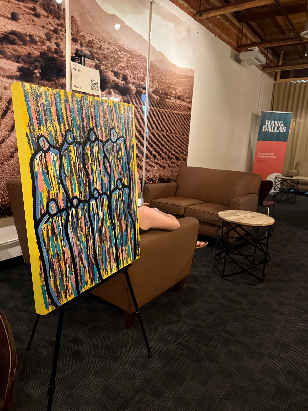 Sierra Barnes&rsquo;s painting Mindset on an easel at a Hang Dallas show, priced and labelled, with the Hang Dallas banner behind it