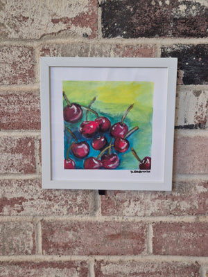 Cherry Season by Dawn Babcock, framed in white and hung on a brick wall